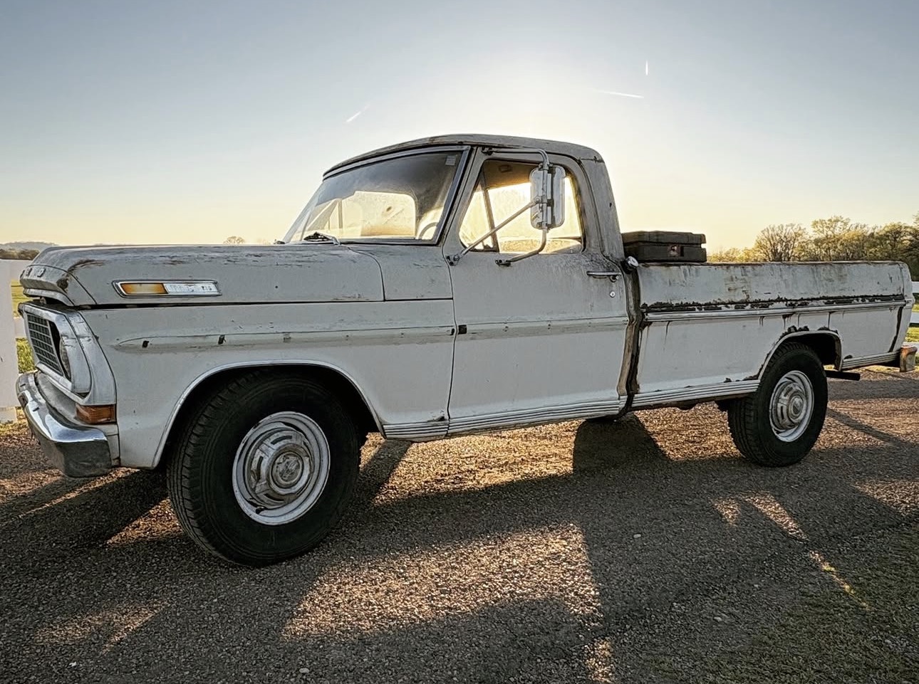 Side profile of the vintage Ford F-250 on a Tennessee gravel road at sunset